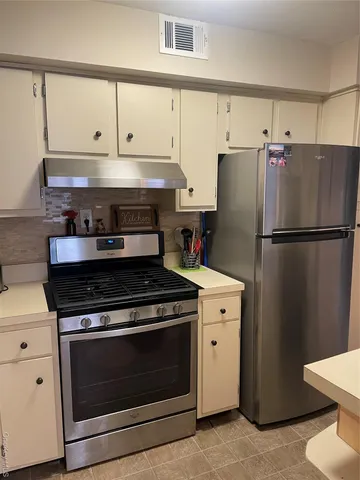 a kitchen with refrigerator a stove and white cabinets