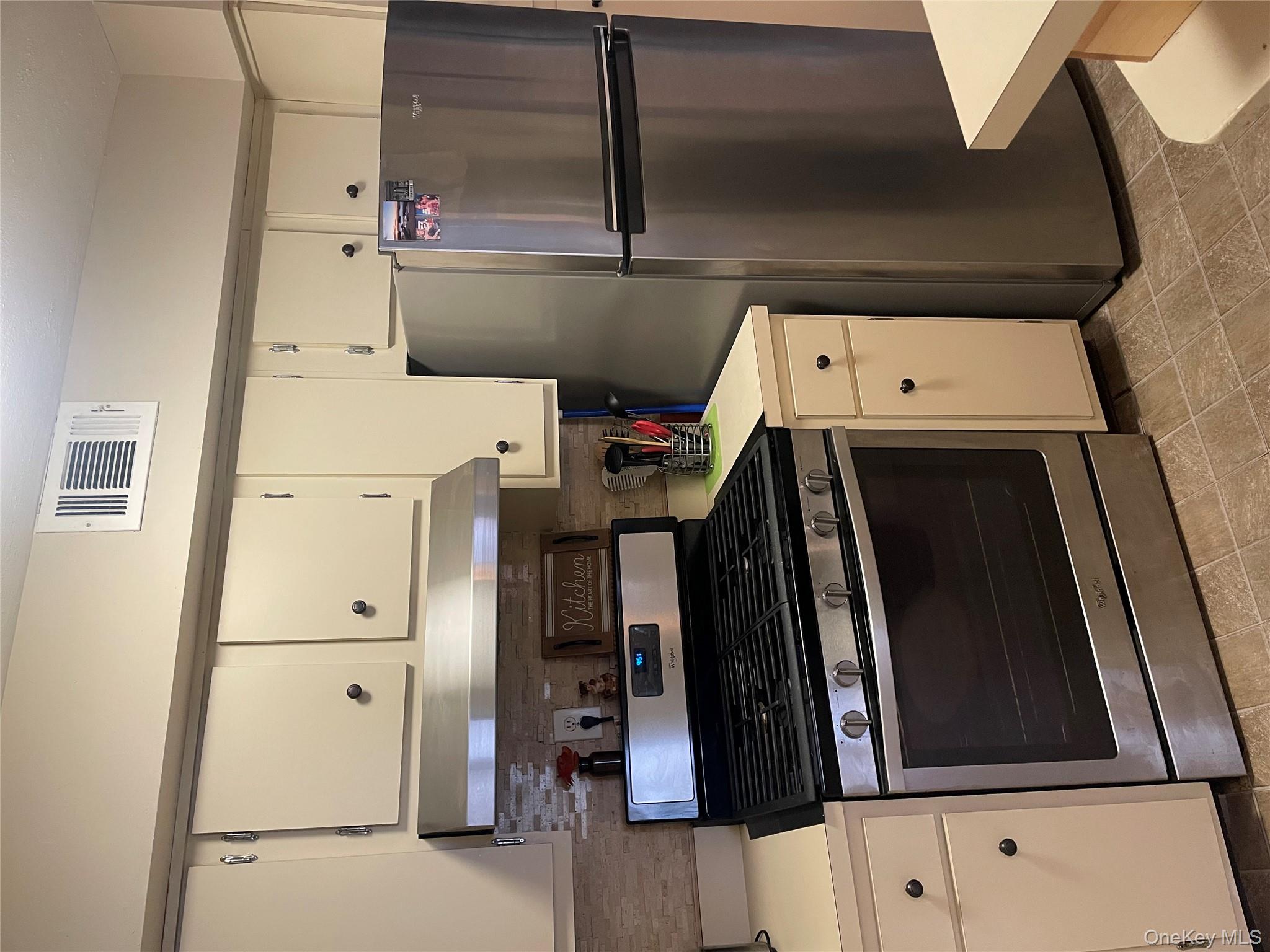 81 Rocky Point Yaphank Road, Unit 145 Rocky Point, NY 11778 - Photo 7 of 11 a kitchen with refrigerator a stove and white cabinets