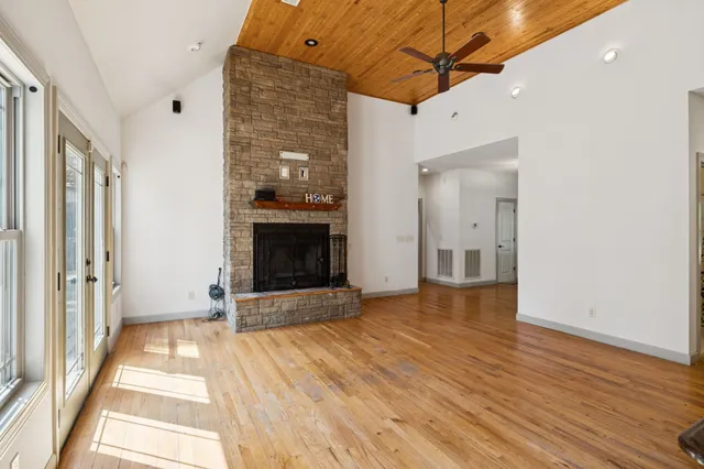 a view of an empty room with wooden floor fireplace and a window