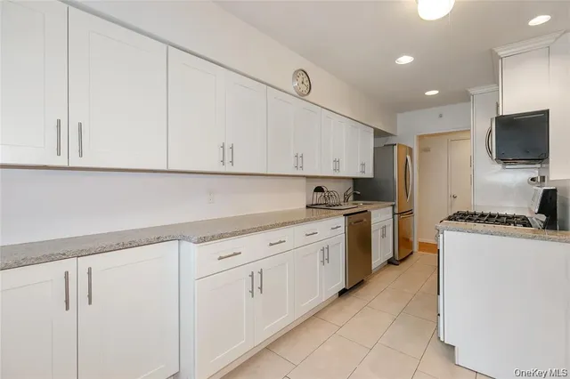 a kitchen with granite countertop white cabinets and stainless steel appliances