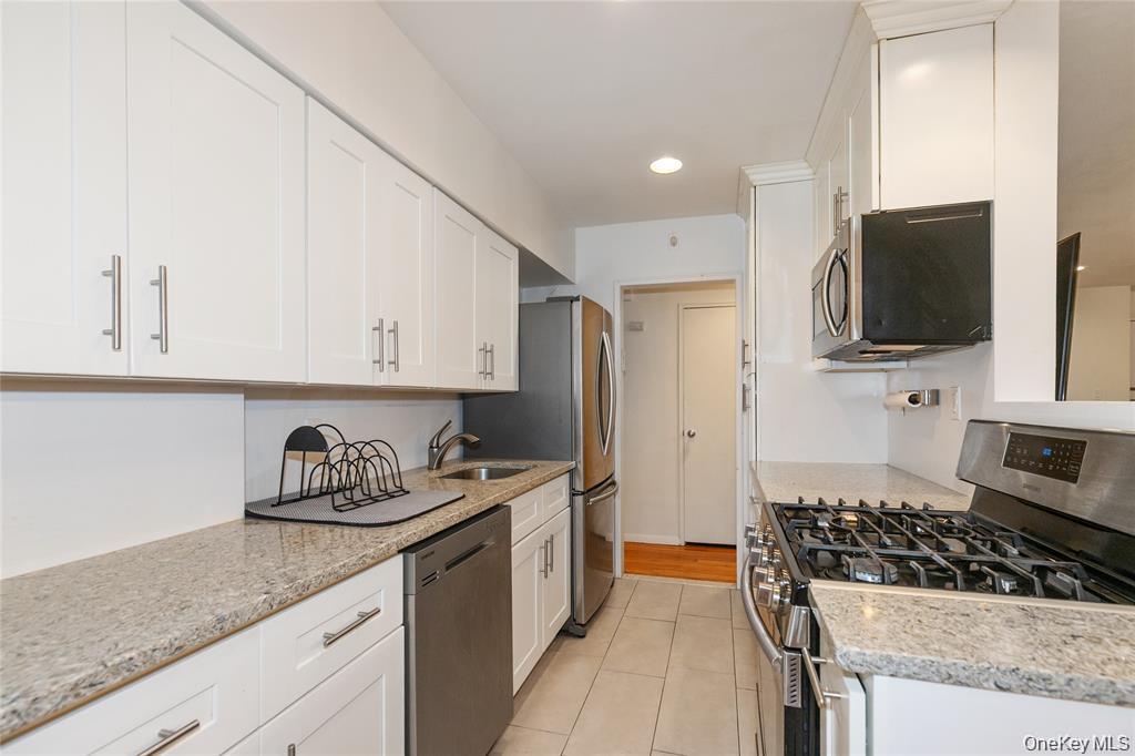 25 Canterbury Road, Unit 2F Great Neck, NY 11021 - Photo 9 of 23 a kitchen with stainless steel appliances granite countertop a sink stove top oven and cabinets