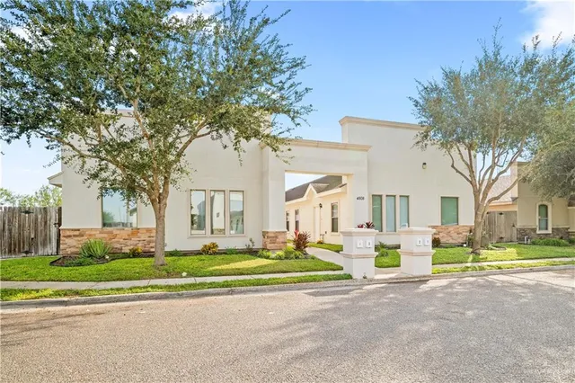 a front view of a house with a garden and trees