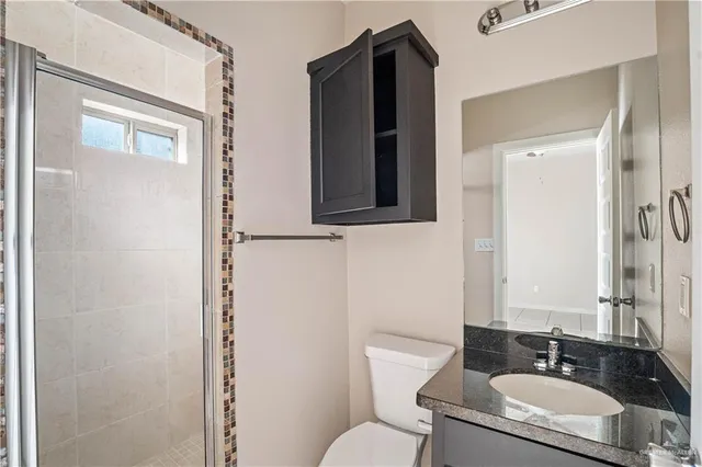 a bathroom with a granite countertop sink toilet and mirror