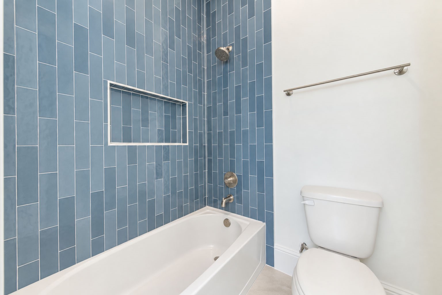 2309 Hollister Road Houston, TX 77080 - Photo 30 of 47 The third bathroom’s tub and shower combination makes a stylish statement with richly textured blue tile extending to the ceiling, creating a sophisticated pop of color and architectural interest. A built-in shower niche and sleek fixtures blend thoughtful functionality with the elevated designer finishes showcased throughout the home.