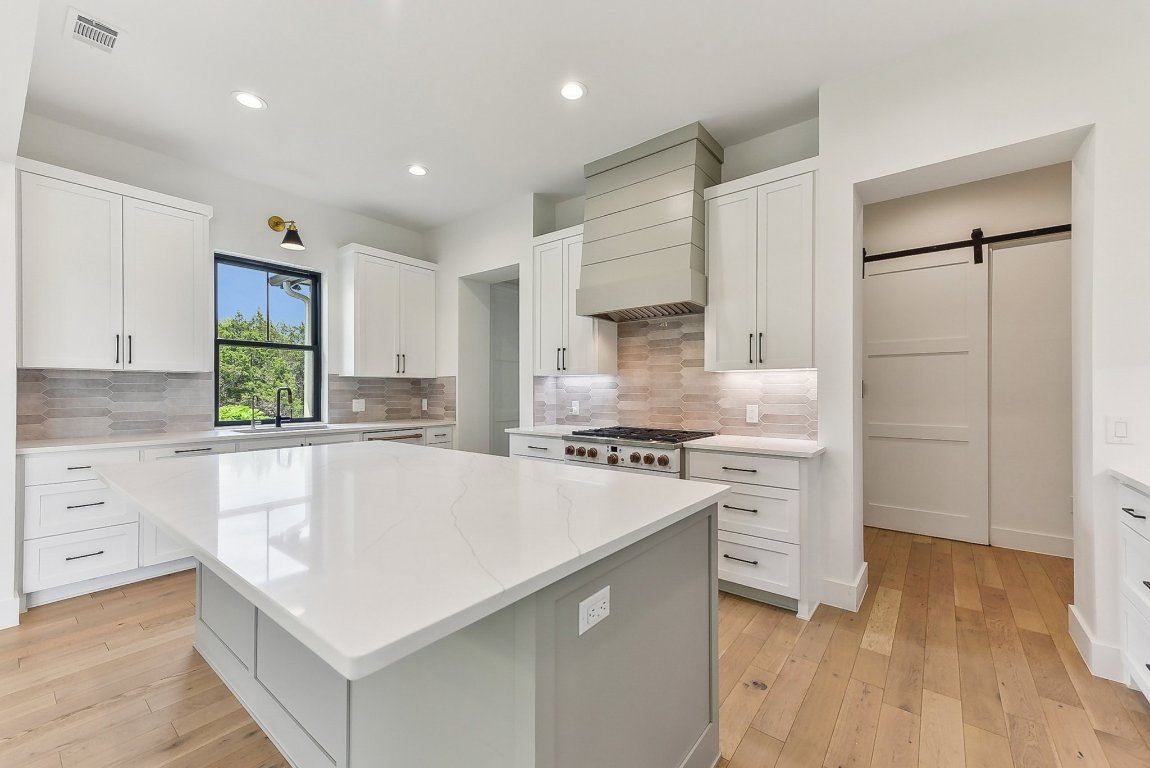 116 Tranquility Trail Spicewood, TX 78669 - Photo 14 of 40 a kitchen with kitchen island a stove a sink and a refrigerator