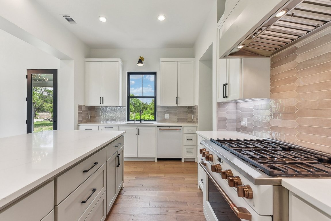 116 Tranquility Trail Spicewood, TX 78669 - Photo 16 of 40 a kitchen with sink a stove and white cabinets