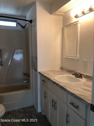 a bathroom with a granite countertop sink a toilet and shower