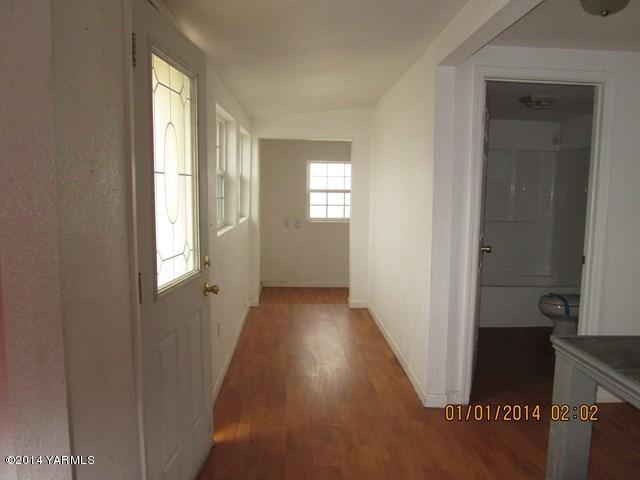 250 Knowles Road Granger, WA 98932 - Photo 6 of 8 a view of a hallway to a livingroom with wooden floor and a window