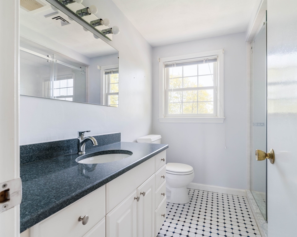 44 Salem Street, Unit C Wakefield, MA 01880 - Photo 17 of 26 a bathroom with a granite countertop sink a toilet a mirror and a window