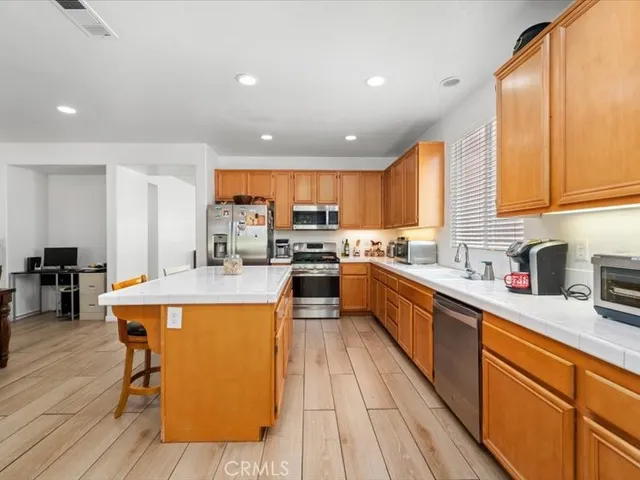 a large kitchen with stainless steel appliances granite countertop wooden floors and white cabinets