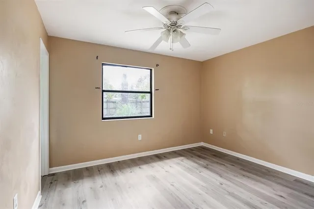 a view of an empty room with window and wooden floor