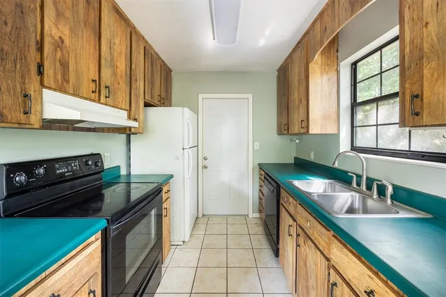 a kitchen with granite countertop a sink a stove and refrigerator