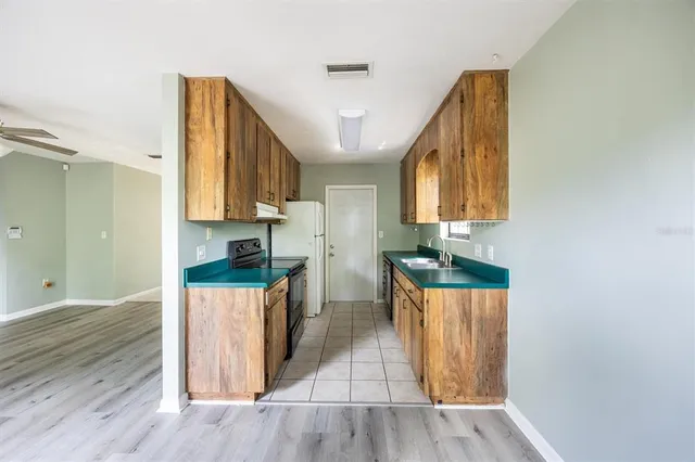 a kitchen with wooden floor and cabinets