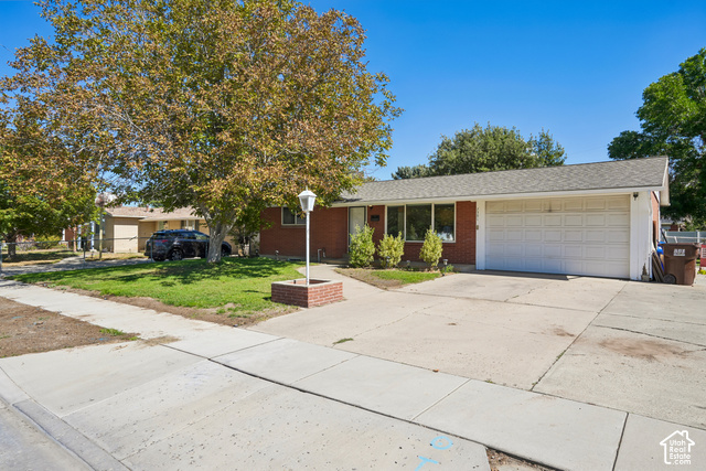 7391 Ramanee Drive Midvale, UT 84047 - Photo 3 of 45 Brick exterior featuring a white garage door, large front windows, and a concrete driveway