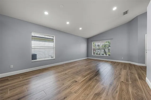 an empty room with wooden floor and windows