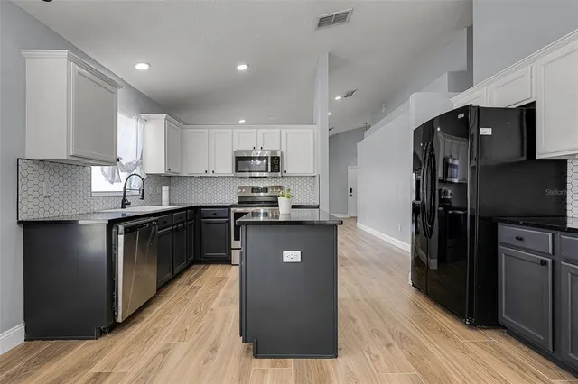 a kitchen with stainless steel appliances granite countertop a sink a stove and a microwave