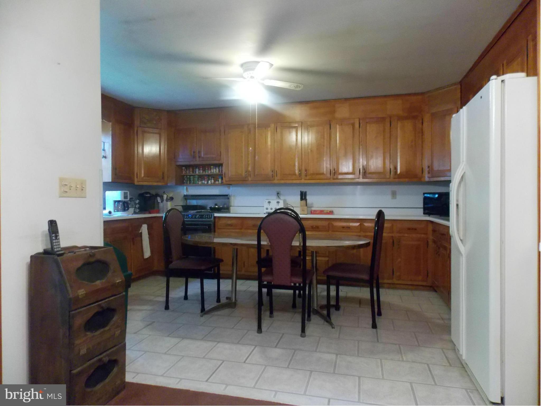 3039 Menges Mill Road Taneytown, MD 21787 - Photo 3 of 25 a kitchen with a refrigerator a table and chairs in it