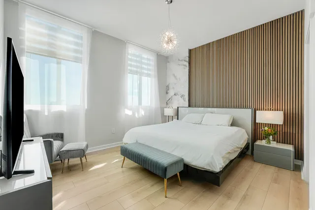 a bedroom with a bed chandelier and a window