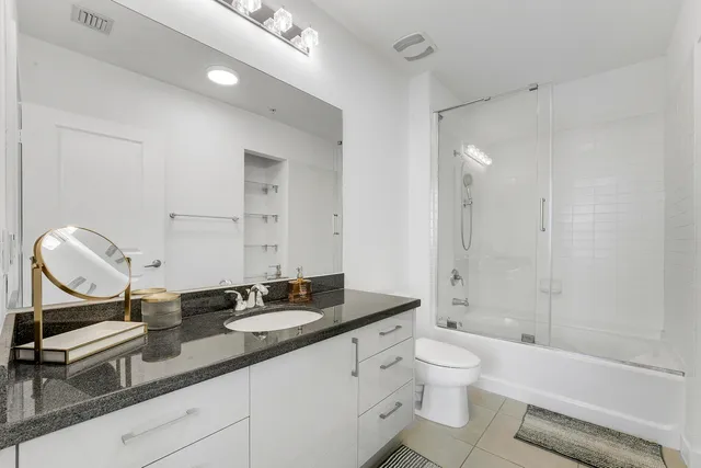 a bathroom with a granite countertop sink a toilet and a mirror