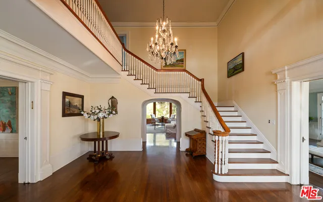 a view of a hallway with wooden floor staircase and a chandelier