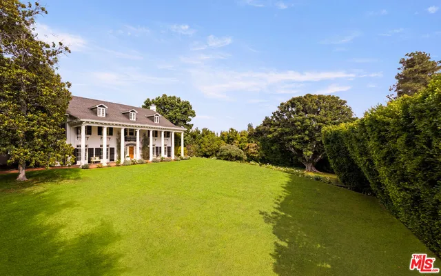 a view of a big house with a big yard and large trees
