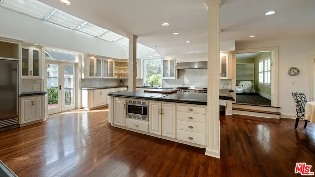 a kitchen with stainless steel appliances kitchen island wooden floors wooden cabinets and view