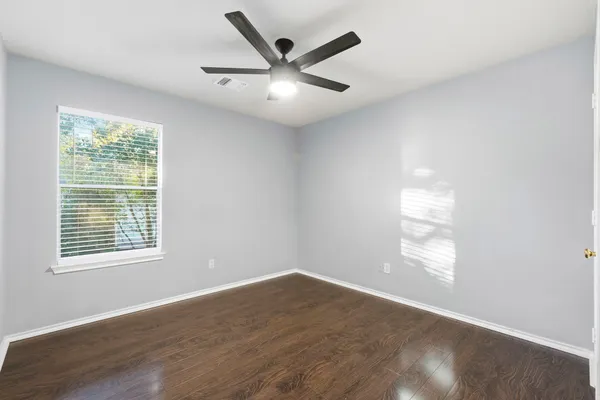 an empty room with wooden floor and windows