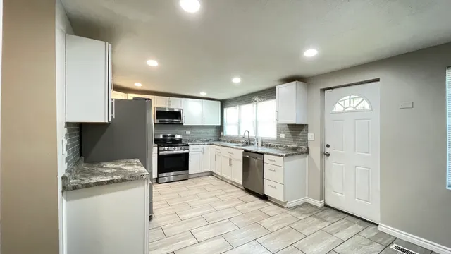 a kitchen with granite countertop stainless steel appliances and white cabinets