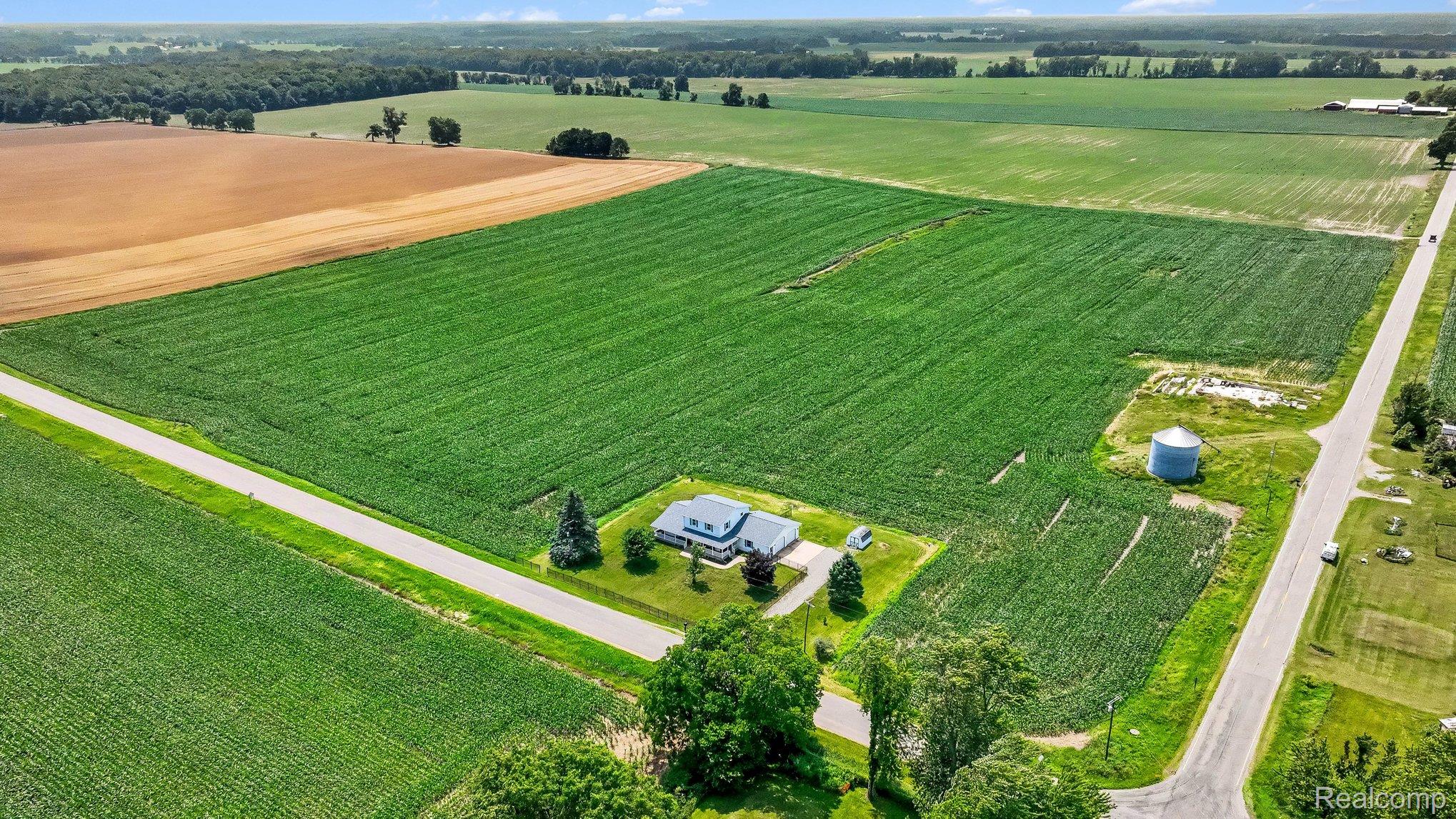 996 Arbogast Road Union City, MI 49094 - Photo 28 of 34 Expansive agricultural property featuring a central residence, surrounding crop fields, a paved road, and a grain silo