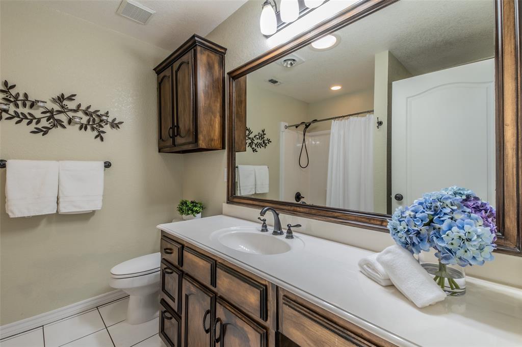 13507 Friendship Road Pilot Point, TX 76258 - Photo 31 of 39 a bathroom with a granite countertop sink a toilet and mirror