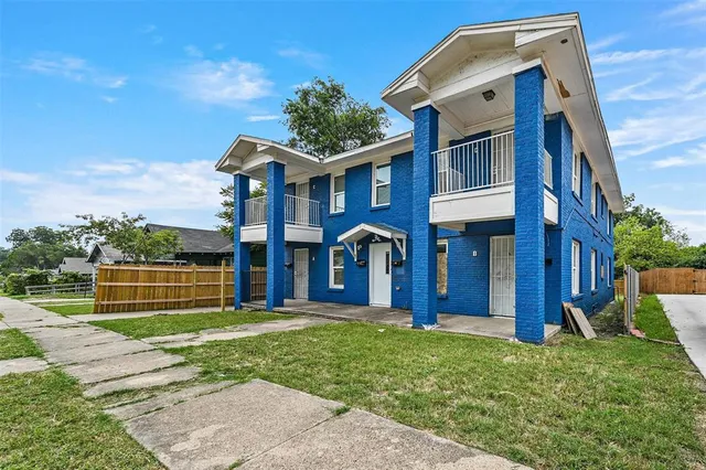 a view of brick house with a yard and plants
