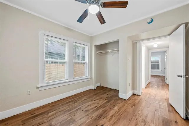a view of empty room with wooden floor and fan