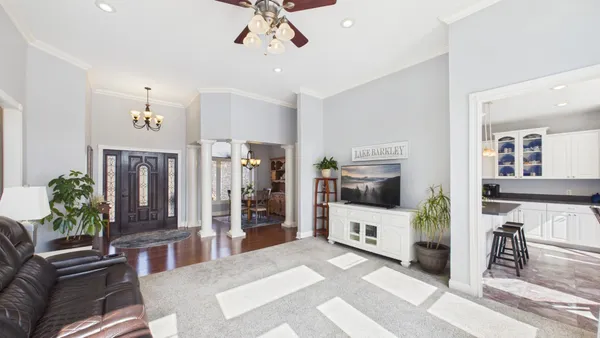 a view of a dining room with furniture a chandelier and large windows
