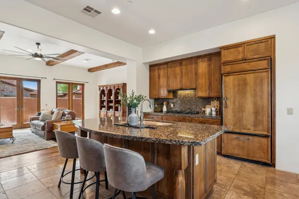 a kitchen with stainless steel appliances granite countertop a stove a refrigerator a sink a dining table and chairs with wooden floor
