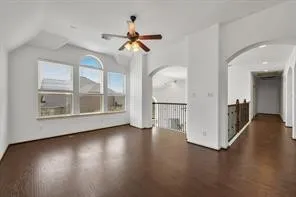 a view of a livingroom with wooden floor a ceiling fan and windows