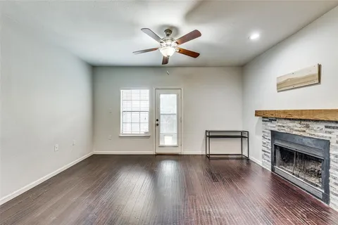 an empty room with wooden floor fireplace and windows