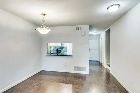 an empty room with wooden floor mirror and windows