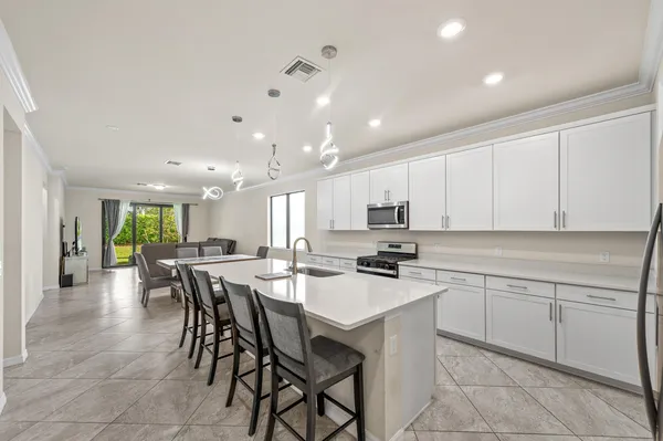 a kitchen with a dining table chairs and white cabinets
