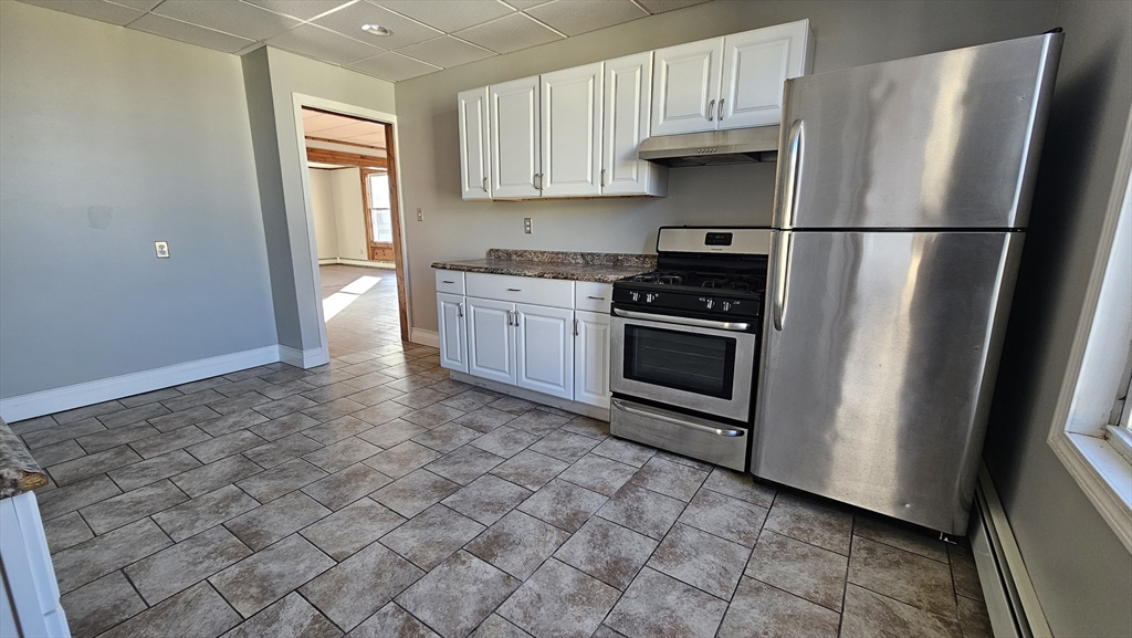 a kitchen with stainless steel appliances granite countertop a refrigerator a stove a sink and a window