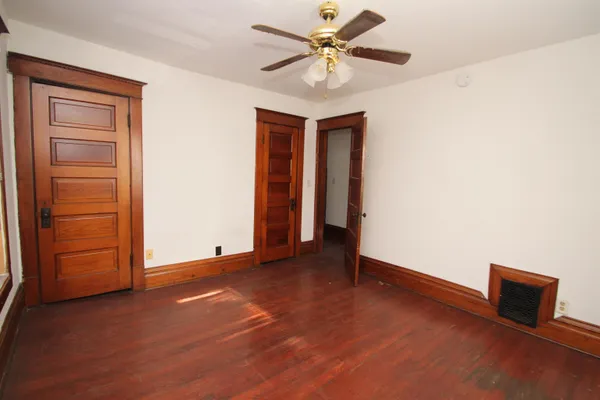 an empty room with closet and a ceiling fan