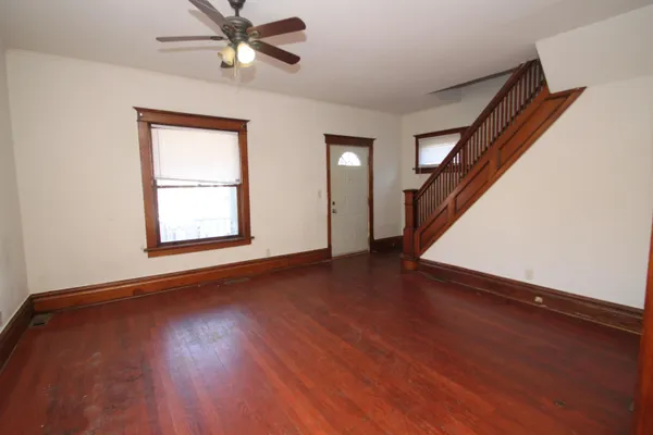 an empty room with wooden floor fan and windows