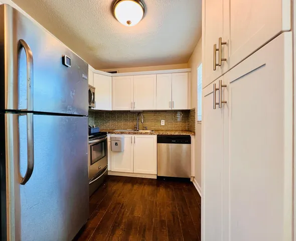 a kitchen with a refrigerator a stove and white cabinets