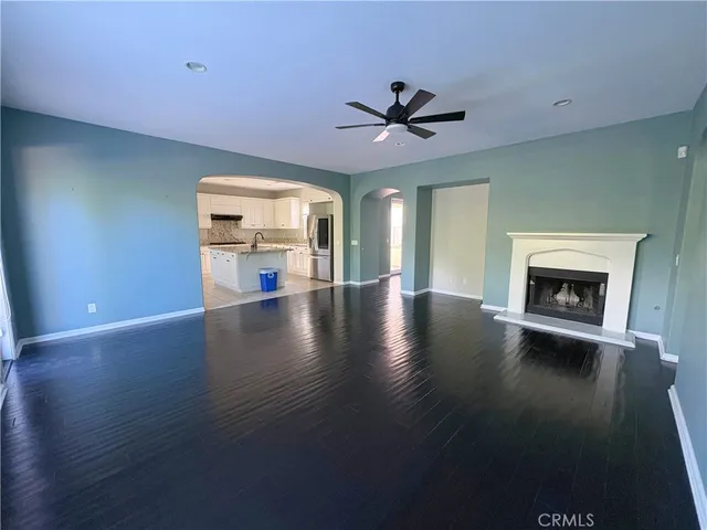 a view of a livingroom with a fireplace a ceiling fan and wooden floor