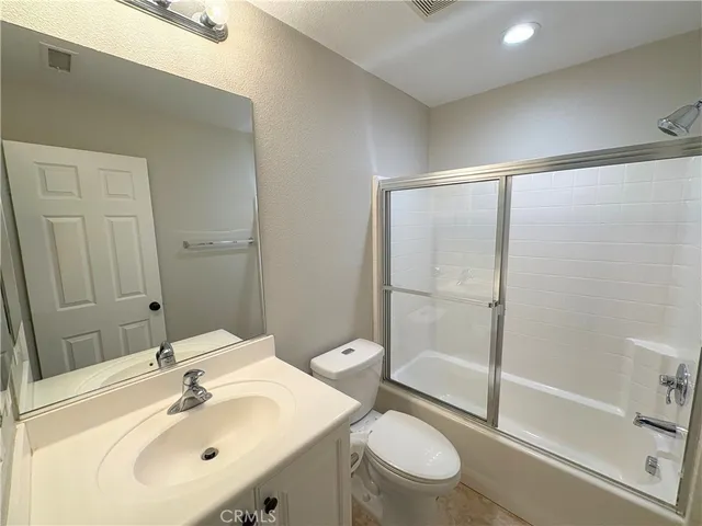 a bathroom with a shower sink vanity mirror and toilet