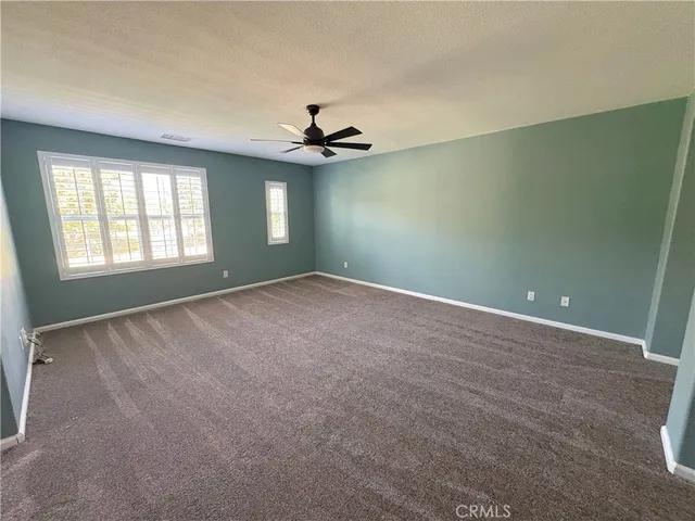 an empty room with windows and ceiling fan