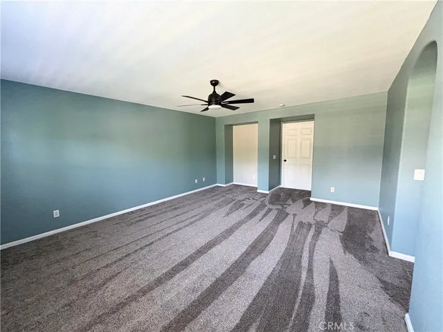 a view of a room with a ceiling fan and hardwood floor