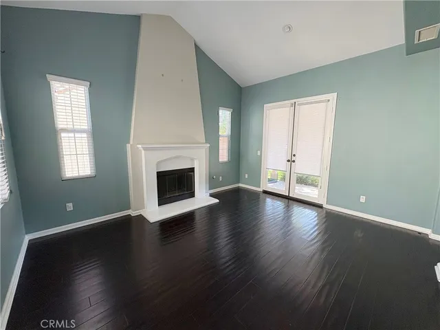 an empty room with wooden floor fireplace and windows
