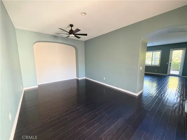a view of a room with wooden floor ceiling fan and a window