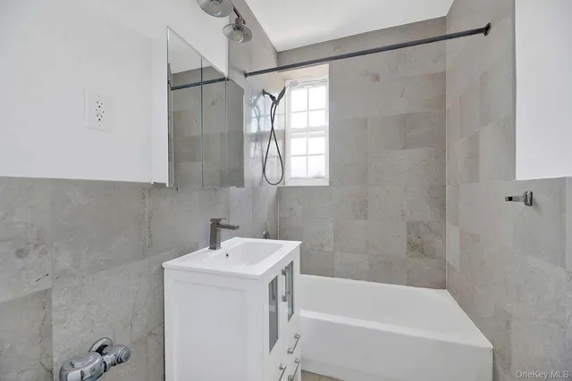 a white bath tub sitting next to a white sink and vanity