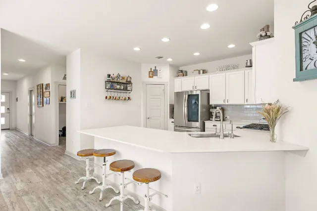 a kitchen with a refrigerator a stove top oven a sink dishwasher and white cabinets with wooden floor